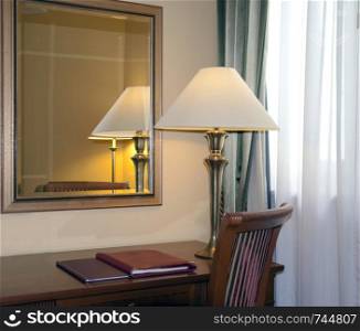 Hotel room with a desk lamp and reflection in the mirror. Hotel room with desk lamp