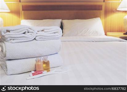 Hotel towel set with toothbrush and toothpaste on white bed