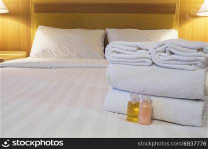 Hotel towel with shampoo and soap bottle set on white bed