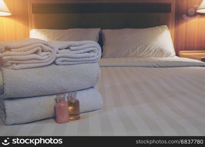 Hotel towel with shampoo and soap bottle set on white bed