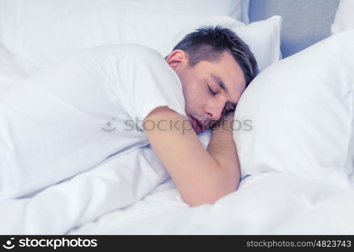 hotel, travel and happiness concept - handsome man sleeping in bed