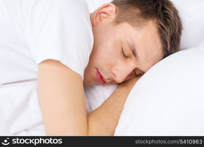 hotel, travel and happiness concept - handsome man sleeping in bed