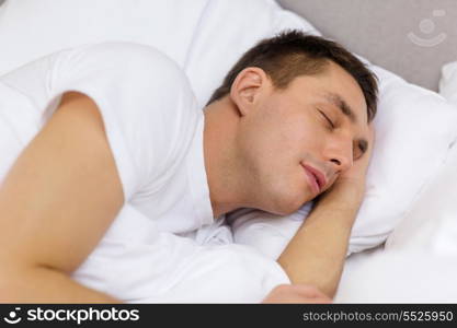 hotel, travel and happiness concept - handsome man sleeping in bed