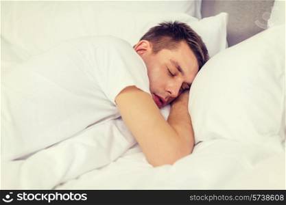 hotel, travel and happiness concept - handsome man sleeping in bed