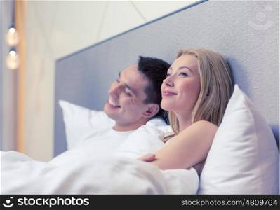 hotel, travel, relationships, and happiness concept - happy couple dreaming in bed