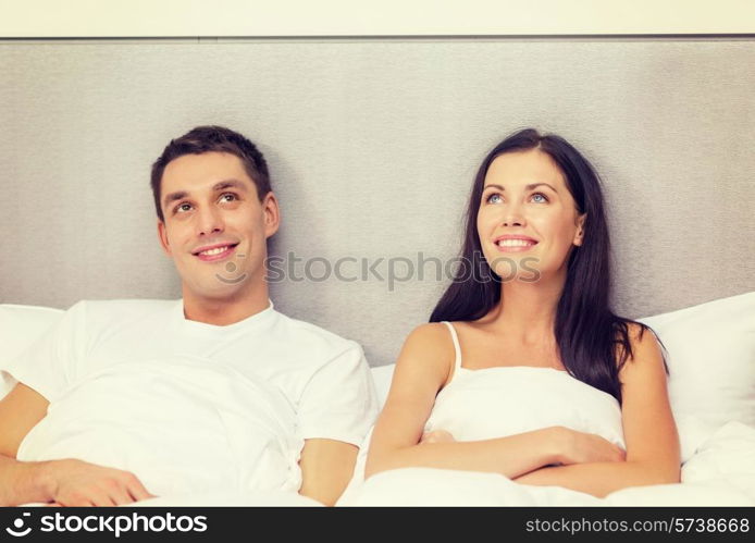 hotel, travel, relationships, and happiness concept - happy couple dreaming in bed