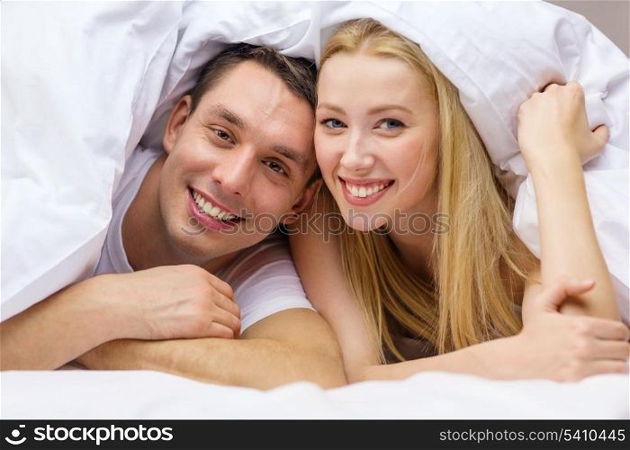 hotel, travel, relationships, and happiness concept - happy couple in bed