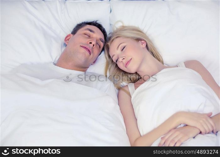 hotel, travel, relationships, and happiness concept - happy couple sleeping in bed