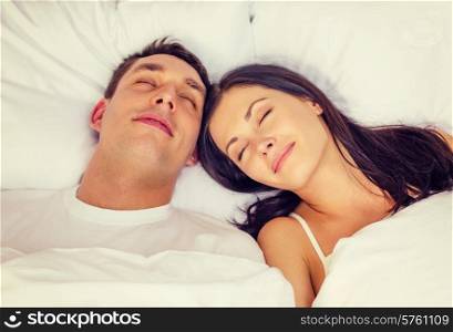 hotel, travel, relationships, and happiness concept - happy couple sleeping in bed