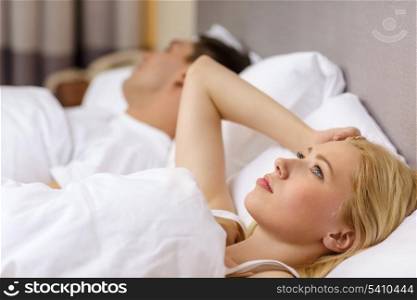 hotel, travel, relationships, and problems with sleep concept - family couple in bed, woman with insomnia