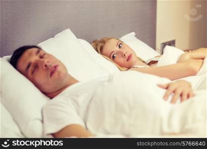 hotel, travel, relationships, and problems with sleep concept - family couple in bed, woman with insomnia