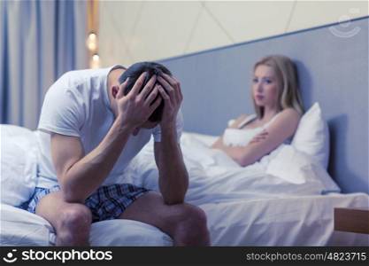 hotel, travel, relationships, and sexual problems concept - upset man sitting on the bed with woman on the back