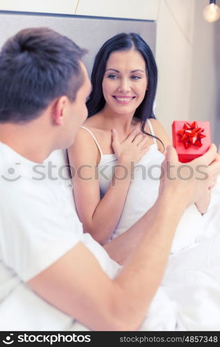 hotel, travel, relationships, holidays and happiness concept - man giving woman little red gift box