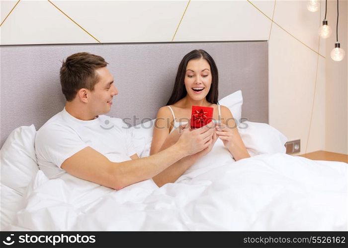hotel, travel, relationships, holidays and happiness concept - man giving woman little red gift box