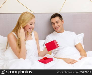 hotel, travel, relationships, holidays and happiness concept - man giving woman little red gift box