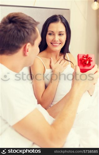 hotel, travel, relationships, holidays and happiness concept - man giving woman little red gift box