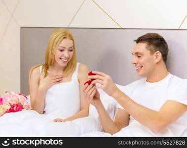 hotel, travel, relationships, holidays and happiness concept - man givnig woman little red box and ring in it