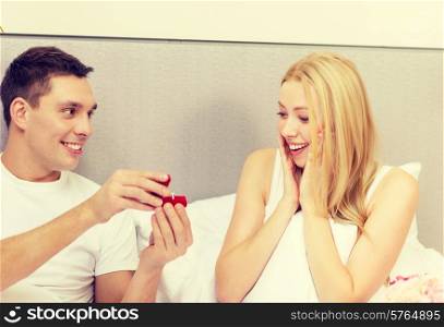 hotel, travel, relationships, holidays and happiness concept - man givnig woman little red box and ring in it