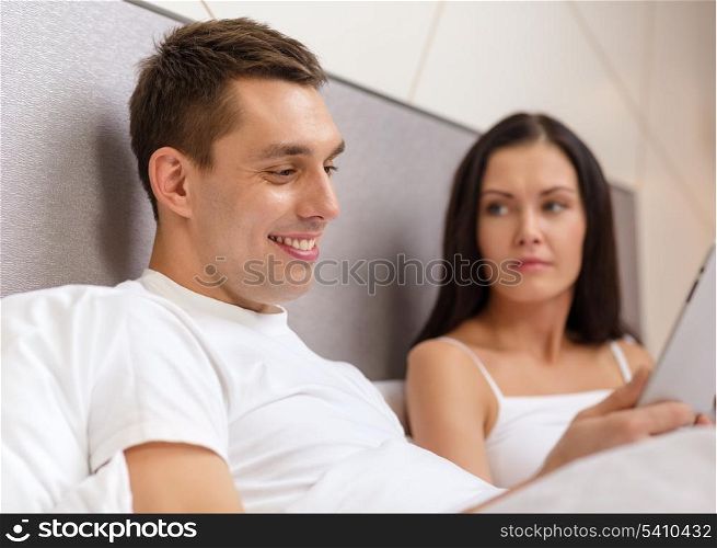 hotel, travel, relationships, technology, intermet and happiness concept - smiling couple in bed with tablet computer