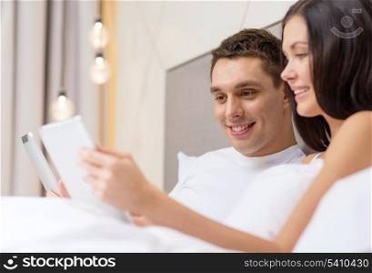 hotel, travel, relationships, technology, intermet and happiness concept - smiling couple in bed with tablet computers