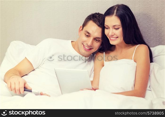 hotel, travel, relationships, technology, intermet and happiness concept - smiling couple in bed with tablet computers