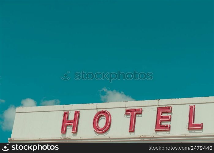 Hotel vintage neon sign text on old building with sky copy space retro color stylized