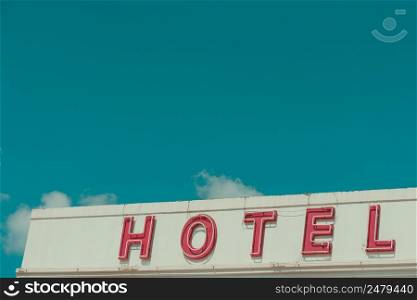 Hotel vintage neon sign text on old building with sky copy space retro color stylized
