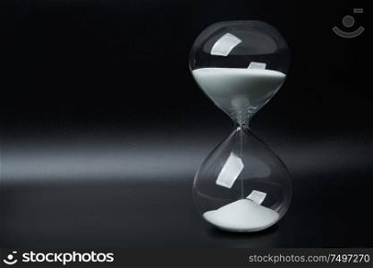 Hourglass or sandglass isolated on black background with copy space. Running time concept