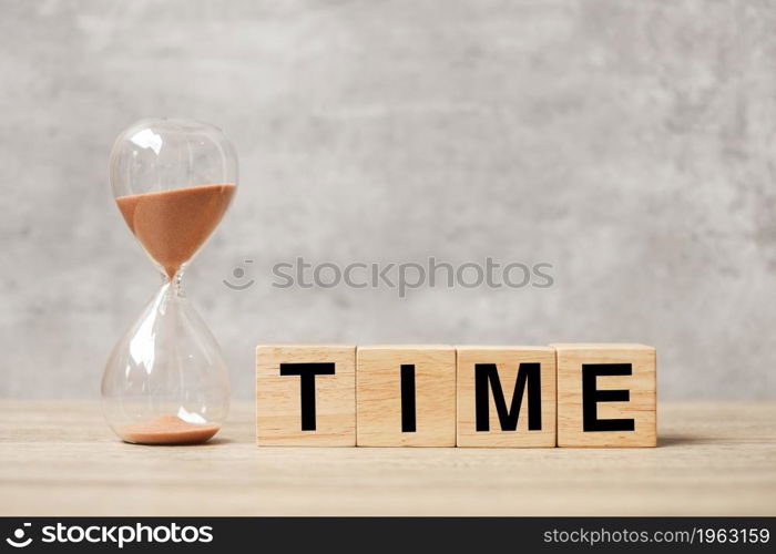 Hourglass with TIME block on table, Sand flowing through the bulb of Sandglass measuring the passing. countdown, deadline, Life time and Retirement concept