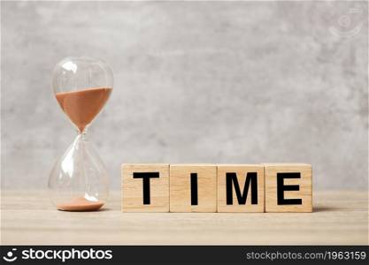 Hourglass with TIME block on table, Sand flowing through the bulb of Sandglass measuring the passing. countdown, deadline, Life time and Retirement concept