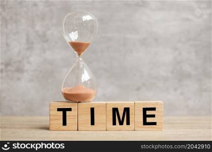 Hourglass with TIME block on table, Sand flowing through the bulb of Sandglass measuring the passing. countdown, deadline, Life time and Retirement concept