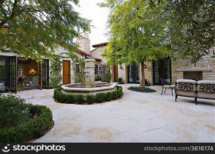House exterior with a fountain trees and patio furniture