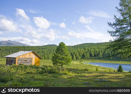 House for rest in taiga against the background of the high mountains of Altai in Russia