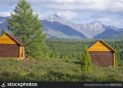 House for rest in taiga against the background of the high mountains of Altai in Russia