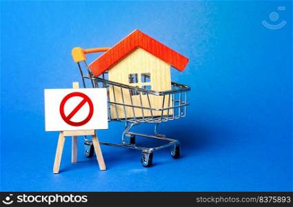 House in a shopping cart and an easel with a red prohibition sign NO. Inaccessibility, lack of housing, deficit. Seizure, freezing of assets by a bank, court. Illegal buildings, demolition elimination