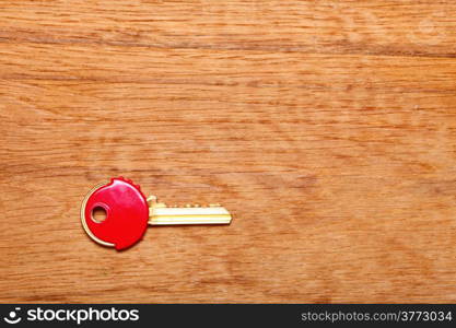 House key with red plastic coats caps on wooden table background. Copy space for text