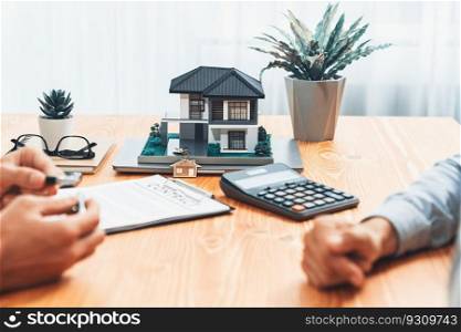 House model is displayed on wooden meeting tab≤with in the blurred background of real estate a≥nt and client discuss terms and conditions of house loan or rental≤ase contract. Entity. House model is displayed on wooden meeting tab≤with blur background. Entity