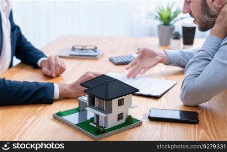 House model is displayed on wooden meeting table with in the blurred background of real estate agent and client discuss terms and conditions of house loan or rental lease contract. Entity. House model is displayed on wooden meeting table with blur background. Entity