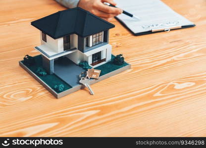 House model is displayed on wooden meeting table with in the blurred background of real estate agent and client discuss terms and conditions of house loan or rental lease contract. Entity. House model is displayed on wooden meeting table with blur background. Entity