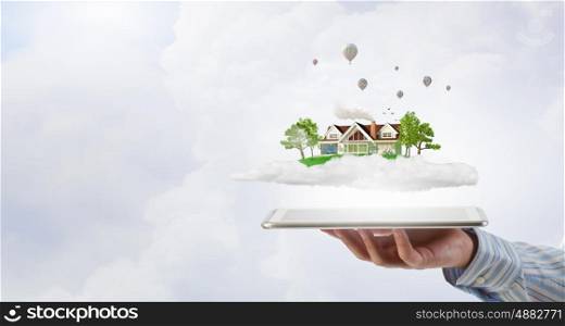 House model. Male hands holding tablet pc with house model on screen