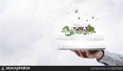 House model. Male hands holding tablet pc with house model on screen