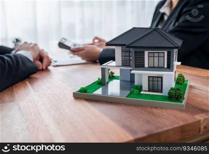 House model s&le on wooden table with blurred background of real estate agent and buyer or client discussing terms and condition on house loan contract. Housing business meeting. Jubilant. House model s&le on wooden table with blurred background. Jubilant