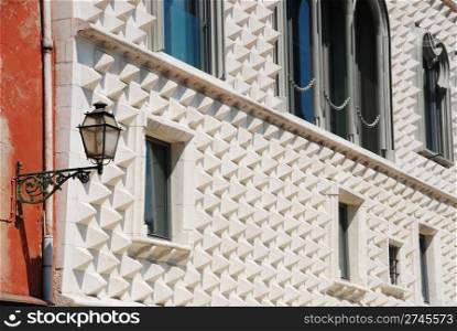 House of diamond-shaped spikes or Casa dos Bicos in the Alfama district in Lisbon, Portugal (focus on antique wall lamp)