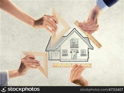 House of dream. Close up of people hands measuring house model with ruler