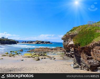 House on cliff and summer Atlantic sunshiny sandy beach Los Castros (Galicia, Spain).