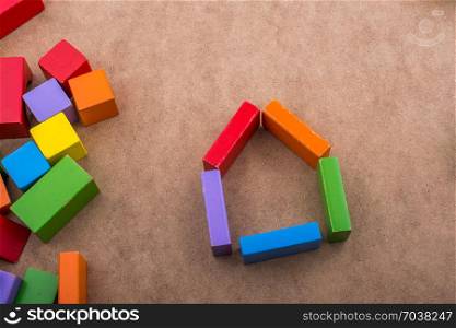 House shape formed out of building blocks on a brown background