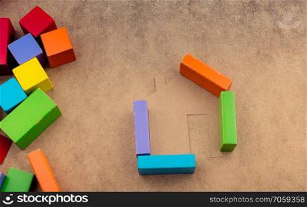 House shape formed out of building blocks on a brown background