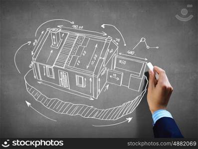 House sketch. Close up image of human hand drawing house project with chalk