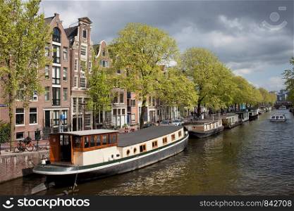 Houseboats and apartment buildings on a canal in the city of Amsterdam, Netherlands.