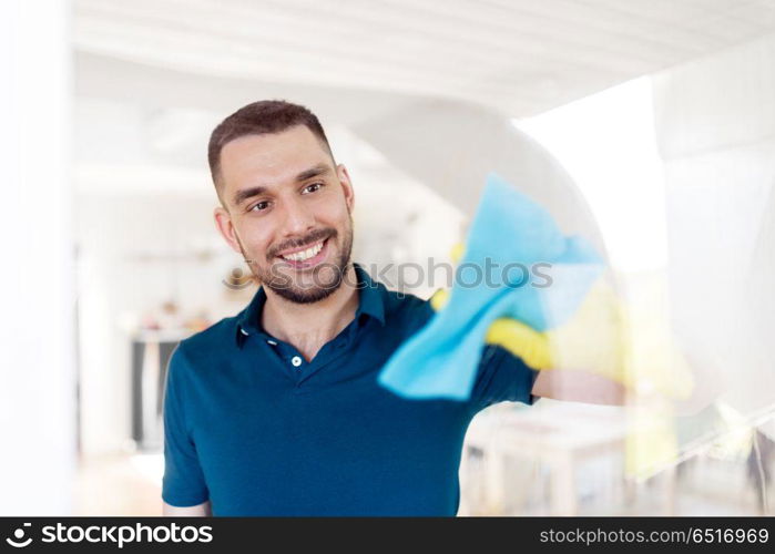 household and people concept - man in rubber gloves cleaning window with rag at home. man in rubber gloves cleaning window with rag. man in rubber gloves cleaning window with rag